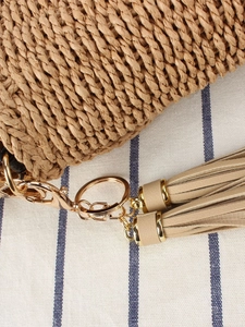 Handmade woven straw crossbody bag with tassel detail and golden metal ring for beach vacation