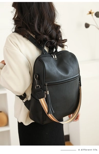 Detail of vintage black leather backpack showing texture and orange woven strap on model
