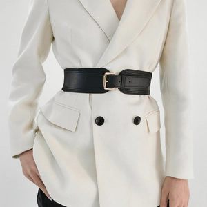 Close-up of black elastic waist belt with gold rectangular buckle on a white blazer