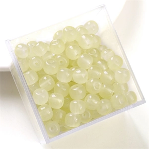 Pale yellow translucent glass beads stored in a transparent square plastic container