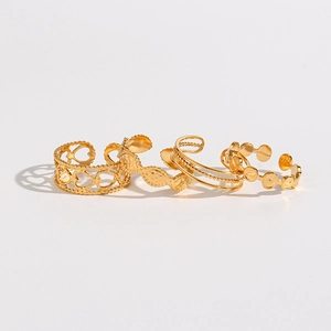 Detailed macro view of four gold stainless steel rings with heart and woven patterns