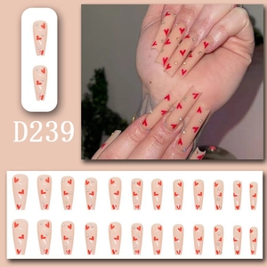 Long coffin press-on nails in nude pink with red hearts and sparkling rhinestones
