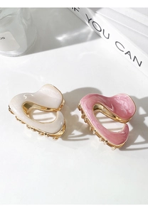 Detail of cream and pink heart hair claws with gold metal base on minimalist desk