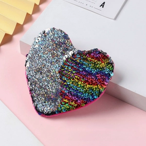 Detail shot of heart-shaped sequin coin purse with silver and rainbow reversible finish
