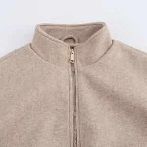 Close-up of beige wool bomber jacket featuring a stand collar and gold metal zipper detail