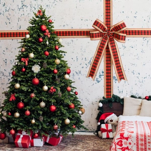Weihnachtsbaum mit roten Ornamenten und großer karierter Schleife für die Heimdekoration