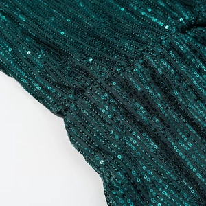 Detailed close-up of dark green sequins on a slim V-neck long sleeve dress fabric