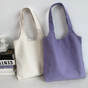 Detail view of cream and purple canvas tote bags with thick durable fabric straps