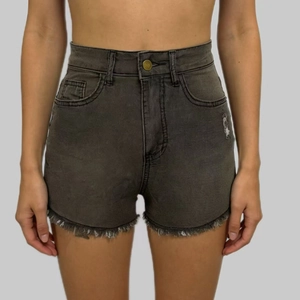 Detail of high waist denim shorts featuring fringe hem and vintage distressed wash effects