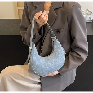 Detail of light blue washed denim crescent bag with silver metallic hardware and handle