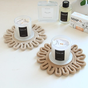 Detail of woven flower-shaped cotton coasters with aromatherapy candles for home decor