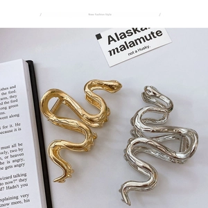 Macro detail of wave snake-shaped metal hair claw clips in polished gold and silver