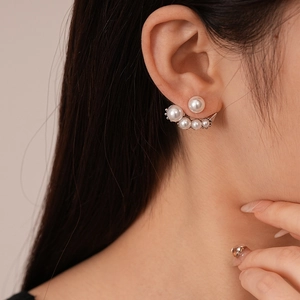 Detail of elegant asymmetric pearl drop earrings on model with silver-tone geometric design