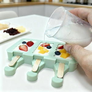 Moule à glace en silicone vert menthe avec fruits frais, bâtonnets et yaourt blanc