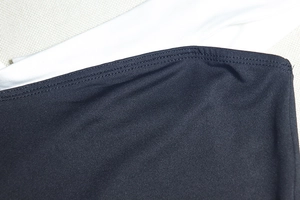 Dettaglio macro delle cuciture sull'abito corto bicolore bianco e nero con scollatura a barca