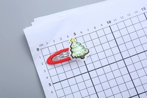Size demonstration of a red Christmas tree hair clip with glitter on a metric scale