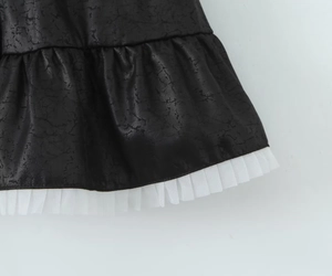 Détail de l'ourlet en similicuir noir avec tulle en maille blanche et bordures volantées