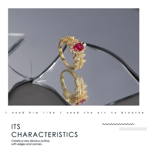 Detailed macro view of an elegant gold ring with a red gemstone and marquise zircons