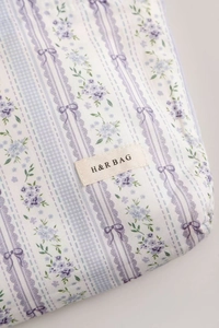 Close-up of floral fabric cosmetics bag with purple patterns and H & R BAG label