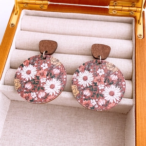 Detail of round wooden earrings featuring vintage floral prints on a linen jewelry box lining