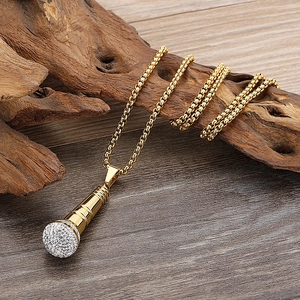 Detail of 18K gold-plated microphone pendant with shiny rhinestones on driftwood