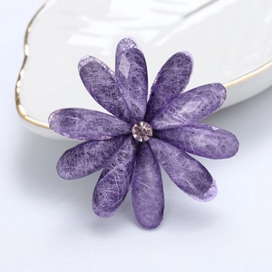 Macro view of purple acrylic flower brooch with delicate petal texture and pink rhinestone