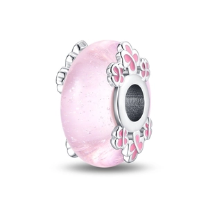 Close-up of pink luminous glass bead with silver floral hollow pattern for DIY jewelry