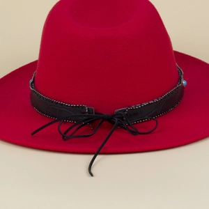 Detailed view of red fedora hat with black crocodile pattern band and blue beads