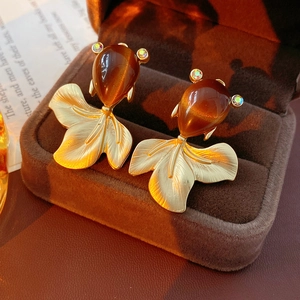 Detail of vintage goldfish earrings with brown cat-eye stone and brushed gold finish