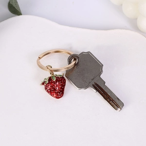 Detail of a red strawberry keychain pendant made of zinc alloy with green leaves