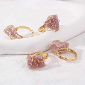 Detail of four handmade wire-wrapped rose quartz rings with gold metal craft