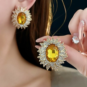 Close-up of vintage golden sunflower earrings with yellow gems and pavé crystals on ear