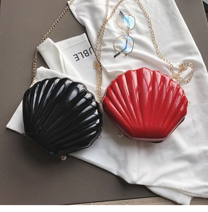 Close-up of shell-shaped evening bags with glossy finish, pearl accents and gold chains