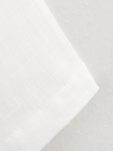 Macro view of white linen fabric texture showing detailed weave and clean hem stitching