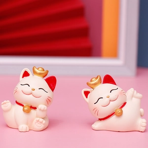Close-up of two miniature resin Lucky Cats in sitting and playful poses for New Year decor