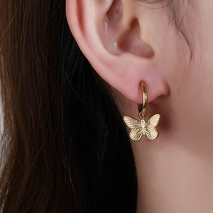 Elegant gold butterfly hoop earrings in titanium steel worn by a female model
