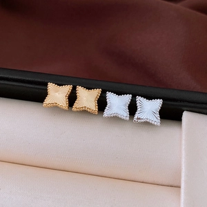 Macro detail of star earrings with radial brushed texture and beaded edges in gold and silver