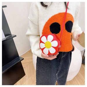 Detail of red flower shaped kids shoulder bag with white petals and smooth texture