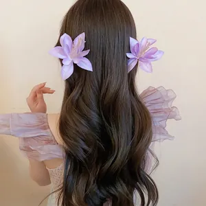 Elegant pair of lavender fabric hibiscus hair clips styled on wavy long brown hair