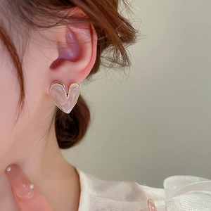 Detail shot of heart-shaped pink marble stud earring with gold edges on model ear