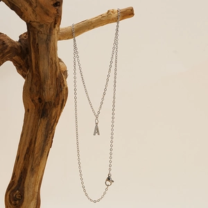Close-up of silver titanium steel letter A pendant necklace on a natural wood branch