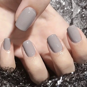 Short square press-on nails in solid neutral grey on a black glitter mesh background