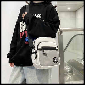 Close-up of a white functional crossbody bag with black mesh pocket and logo detail