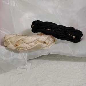 Detail of woven hairbands in black and cream with gold heart chain charms on silk fabric