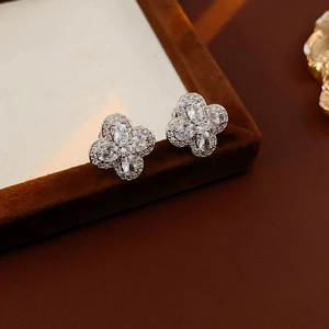 Boucles d'oreilles trèfle en argent avec zircons sur une boîte à bijoux en velours noir