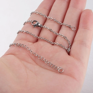 2mm stainless steel cross chain necklace with lobster clasp held on palm over white background