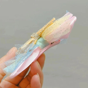 Detail of pink mesh bow hair clip with gold textured center and glitter rhinestones
