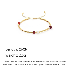 Detail showing adjustable string bracelet with gold beads, red stones and a white pearl