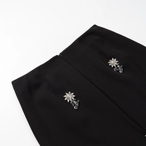 Détail de la taille d'une jupe noire avec fleur en strass et fermeture éclair invisible