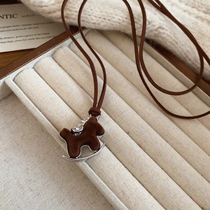 Detailed view of rocking horse necklace with brown flocking, silver metal and zircon accents